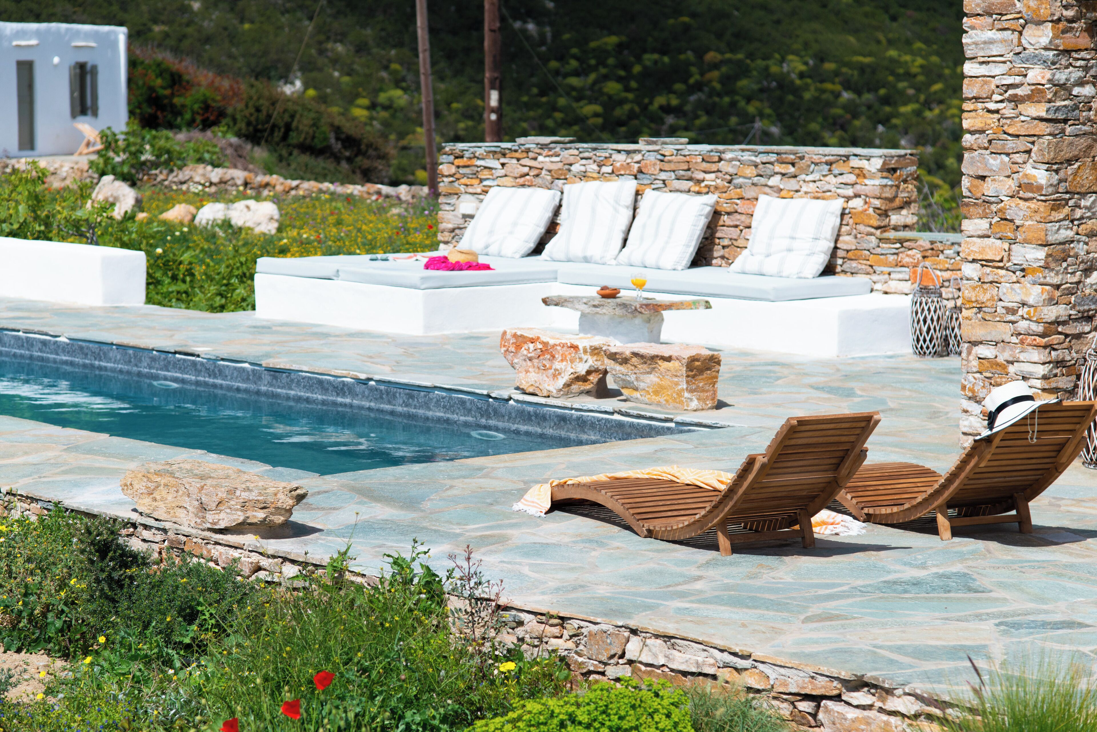 Area piscina con lettini e parete in pietra.