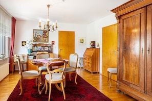A dining area with a wooden table, chairs, a chandelier, and a large wooden cabinet. - Apartment 'Kropp' with Mountain View, Balcony, and Wi-Fi (Steinen)