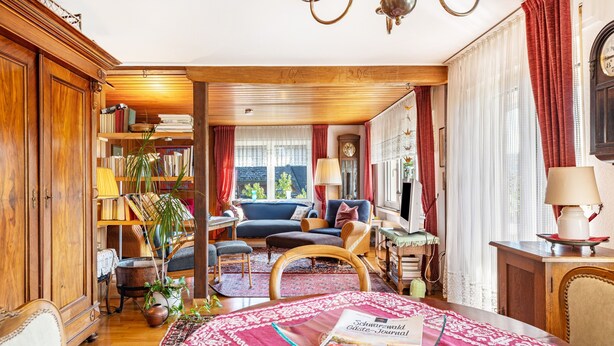 A cozy living room with a sofa, a coffee table with a magazine, a bookshelf, and a window with curtains. - Apartment 'Kropp' with Mountain View, Balcony and Wi-Fi (Steinen)