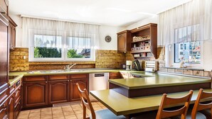A kitchen with a large island, wooden cabinets, a dishwasher, and a window with a view of greenery. - Apartment 'Kropp' with Mountain View, Balcony and Wi-Fi (Steinen)