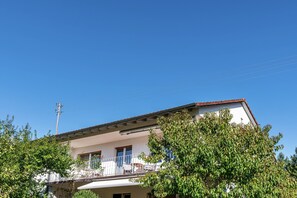 A two-story building with a balcony, a power line, and a tree in the foreground. - Apartment 'Kropp' with Mountain View, Balcony, and Wi-Fi (Steinen)