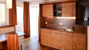 A modern kitchen with wooden cabinets, a dining table, and a pendant light. - Apartment 'Gipfelglück 1' with Mountain View, Shared Terrace and Wi-Fi (Malles Venosta)