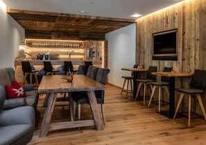 A modern interior with a wooden bar, seating area, and a flat-screen TV mounted on a wooden wall.