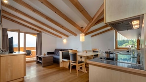 Una cocina moderna con vigas de madera, un comedor con mesa y sillas, y un sofá.