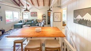 A cozy living room with a wooden dining table, two chairs, a green sofa, and a fireplace.