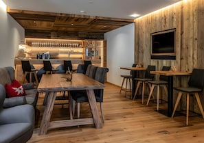 A modern interior with a wooden bar, seating area, and a flat-screen TV mounted on a wooden wall.