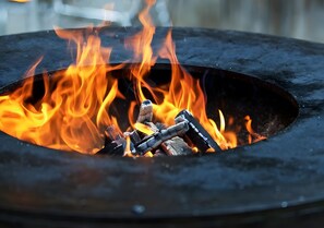 A close-up of a fire pit with flames and logs.