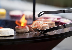 A grill with sausages and a white object, possibly a cheese, being cooked.