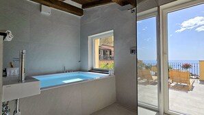 A bathroom with a bathtub, a window, and a view of the sea. - The Pirate's Penthouse- Bluchalet  (Riomaggiore)