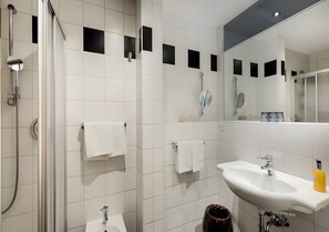 Une salle de bain moderne avec une douche à parois de verre, un lavabo blanc et un miroir.