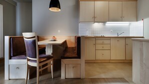 Una cocina moderna con armarios de madera, una zona de comedor con banco y una lámpara colgante.
