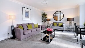A modern living room with a grey sofa, a coffee table, a dining table, and two lamps. - Spacious 3 Bed in Aberdeen s Westend (Aberdeen)