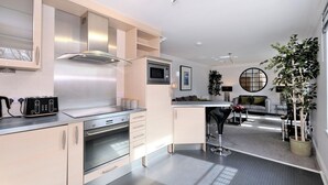 A modern kitchen with stainless steel appliances, a built-in microwave, and a toaster. There is a dining area with a round table and chairs. - Spacious 3 Bed in Aberdeen s Westend (Aberdeen)