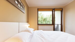 Ein Hotelzimmer mit einem großen Bett, einem Fenster mit Blick auf Bäume und einem Wandbild.