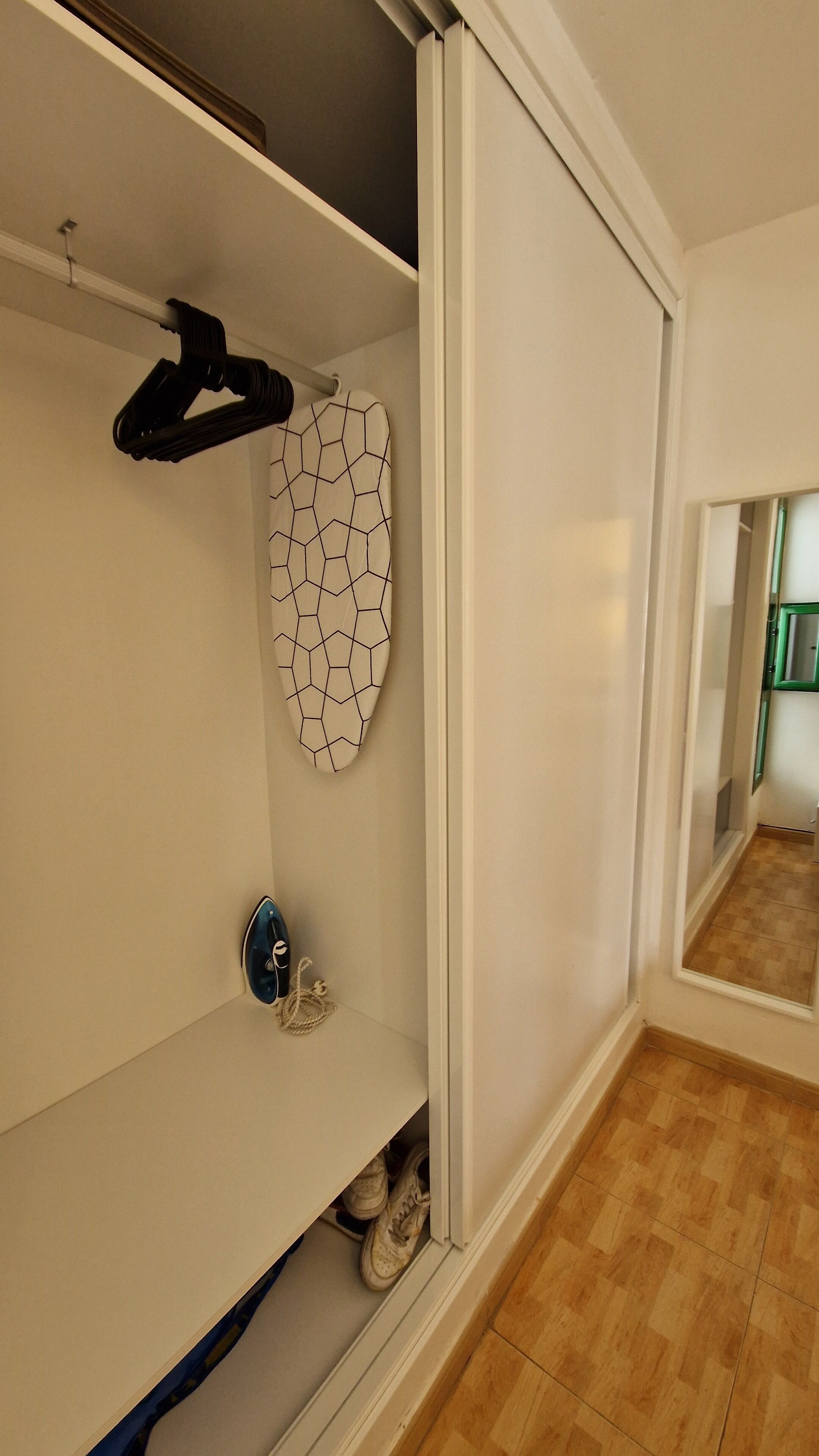 A room with a white wardrobe, a ceiling fan, and a patterned wall hanging.
