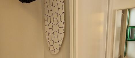 A room with a white wardrobe, a ceiling fan, and a patterned wall hanging.