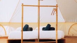 A single bed with a wooden frame and a hanging light fixture in a tent-like room.