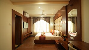 Habitación de hotel con cama, escritorio, silla, espejo y ventilador de techo.