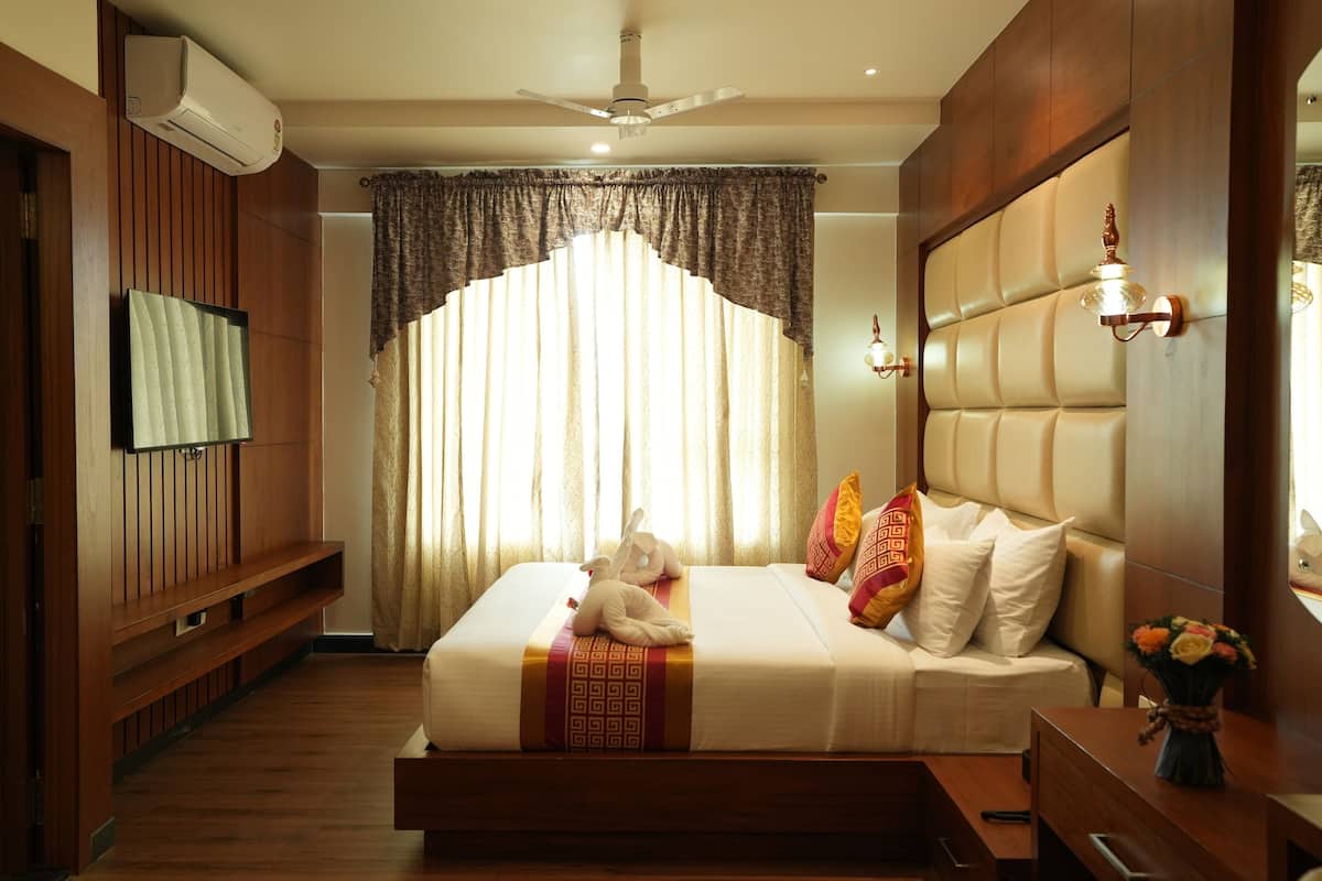 Ein Hotelzimmer mit Bett, Holzwandverkleidung, Fernseher, Deckenventilator und einem Fenster mit Vorhängen.