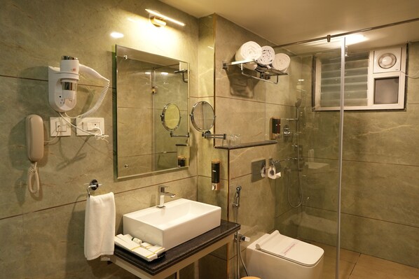 A modern bathroom with a sink, mirror, towel rack, and a glass-enclosed shower area.