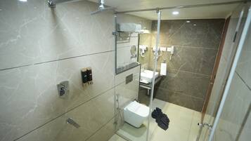 A modern bathroom with a glass-enclosed shower, marble walls, and a glass shower door.