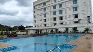 Una piscina con borde de baldosas, rodeada por un edificio con varias ventanas y balcones.