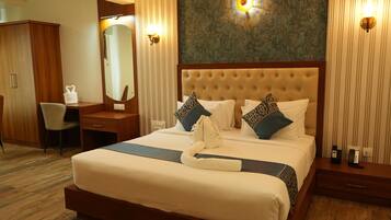 A hotel room with a large bed, a desk, a chair, a wardrobe, and a mirror.