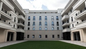 A modern multi-story building with a central courtyard, balconies, and a flat roof. - Nest Inn Boucle Apartment (Baia Mare)