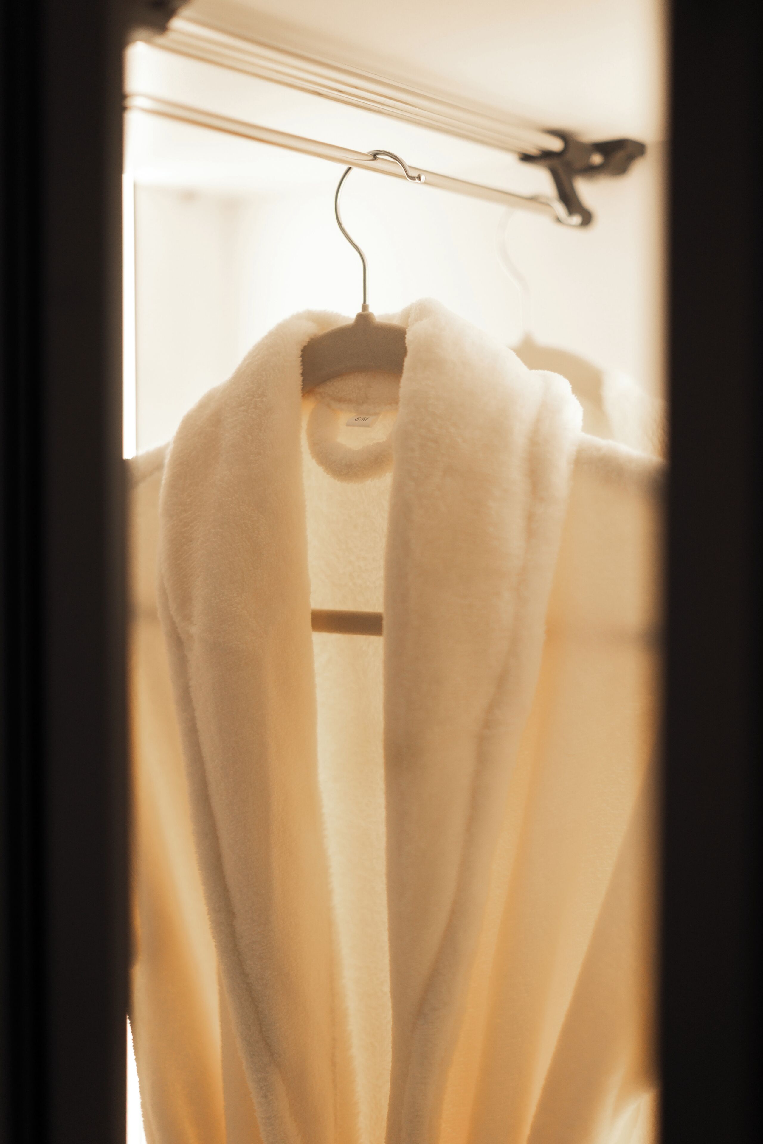 Un robe blanco colgado en un perchero metálico en una habitación bien iluminada.