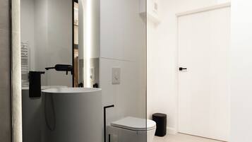 A modern bathroom with a large mirror, a toilet, and a sink.