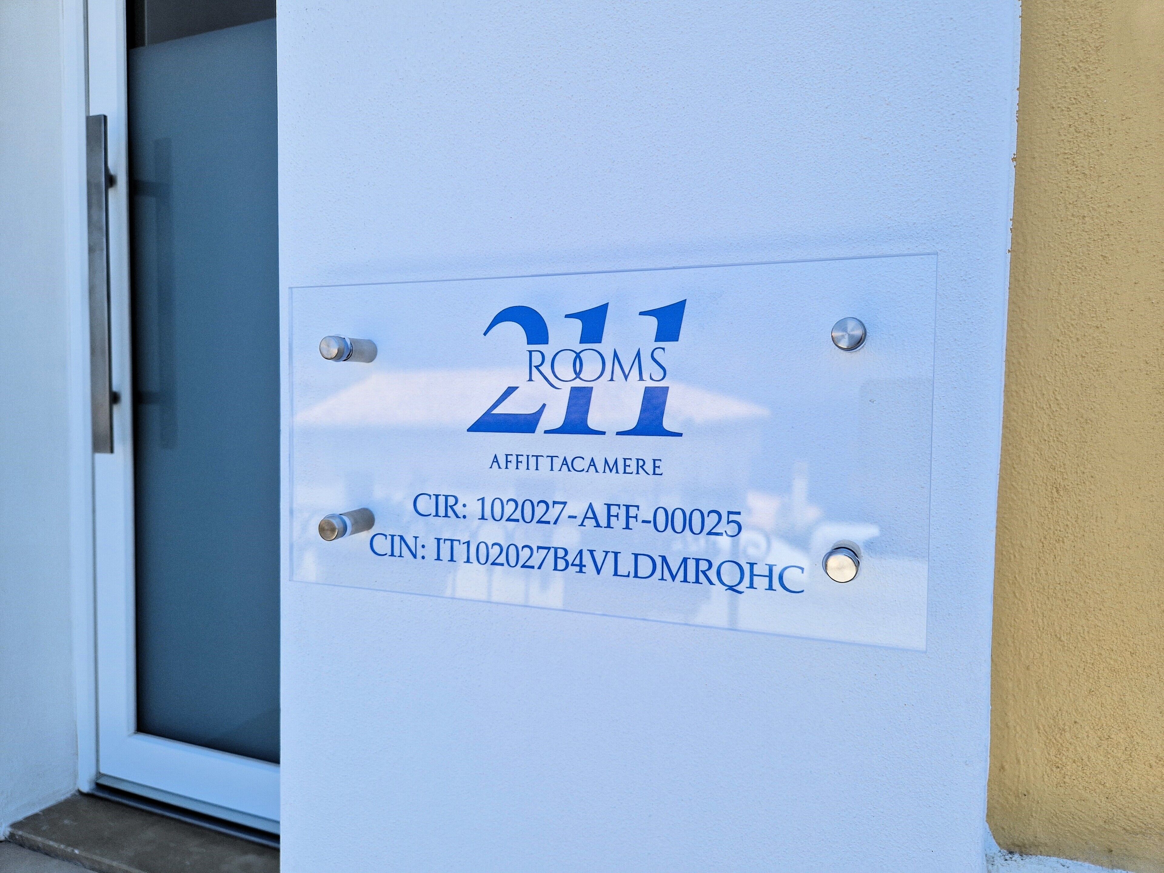 A door with a sign indicating 'Rooms 211' and 'AFFITTACAMERE' along with contact information.