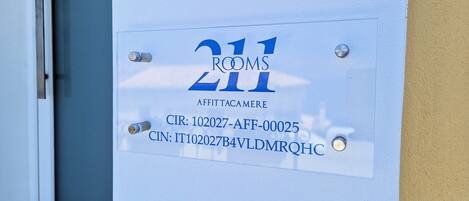 A door with a sign indicating 'Rooms 211' and 'AFFITTACAMERE' along with contact information.