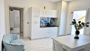 A modern kitchen with white cabinets, a marble backsplash, and a dining area with a white table and chairs. - Al 211 Rooms (Pizzo)