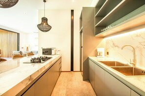 Una cocina moderna con encimera de mármol, pileta de acero inoxidable y una lámpara colgante.