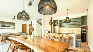 A modern kitchen with a central island, wooden chairs, and hanging pendant lights. - Coastal Haven: Fresh 4BR Villa 200m to Canggu (Canggu)