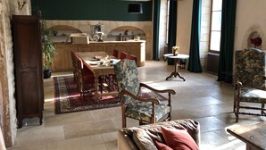 Un amplio salón con una mesa de comedor, sillas, un sofá y una cocina al fondo.