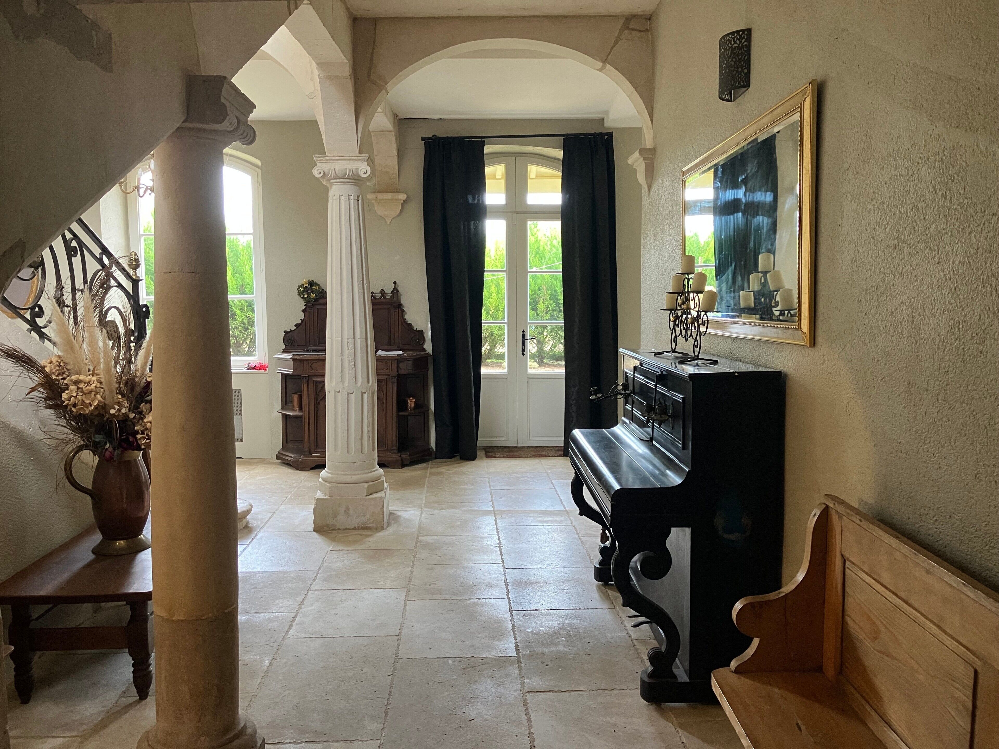 A grand room with a piano, a large mirror, and a column.