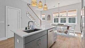 A modern kitchen with a central island, stainless steel appliances, and a dining area with a white table and chairs.