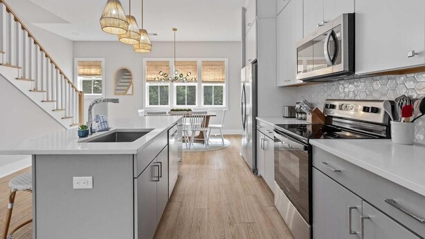 A modern kitchen with a central island, stainless steel appliances, and a dining area with a chandelier.