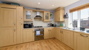 Una cocina moderna con armarios de madera, microondas integrado, estufa y pileta.