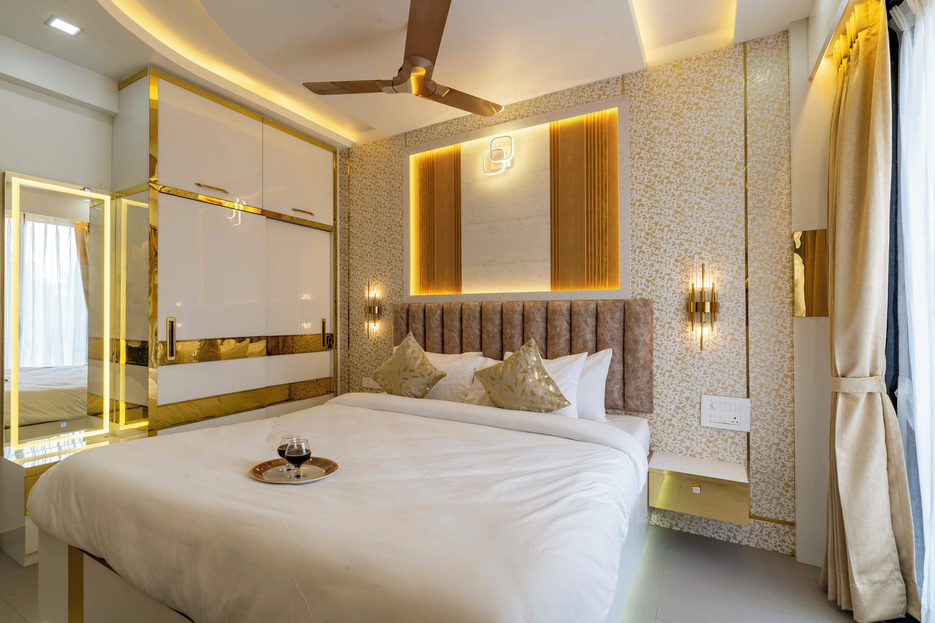 Une chambre d’hôtel moderne avec un grand lit, un ventilateur de plafond et un panneau décoratif mural.
