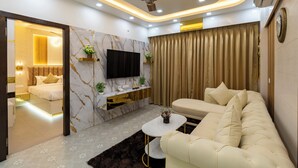 A modern living room with a sofa, a coffee table, a TV mounted on the wall, and a ceiling fan.