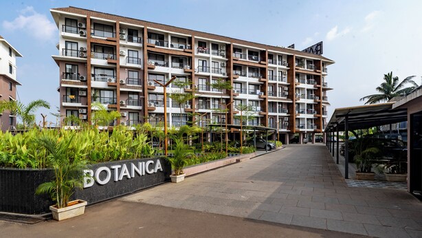 A multi-story residential building with balconies, air conditioning units, and a sign reading "BOTANICA".