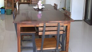 Un comedor con una mesa y sillas de madera, un ventilador de techo, un microondas, un refrigerador y un dispensador de agua.