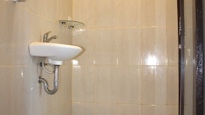 Un baño con un lavamanos blanco, una repisa de vidrio y un espejo.