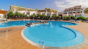 A swimming pool with a tiled deck, a building with 'Santa Marina' signage, and a clear sky. - SeaShell Crown Luxury Suite (Costa Adeje)