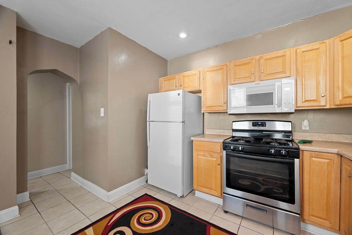 A kitchen with wooden cabinets, a white refrigerator, a microwave, and a stove.