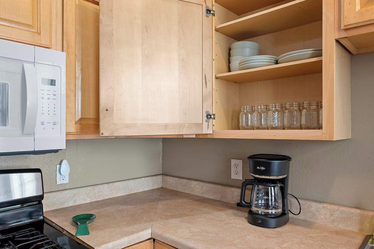A kitchen with wooden cabinets, a microwave, a coffee maker, and a stove.