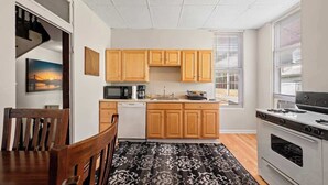 Cocina moderna con armarios de madera, microondas, estufa y un comedor con mesa y sillas.