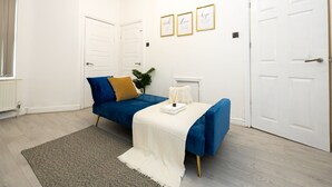 Ein Schlafzimmer mit zwei Betten, einem weißen Heizkörper, einem grauen Teppich und drei gerahmten Bildern an der Wand.